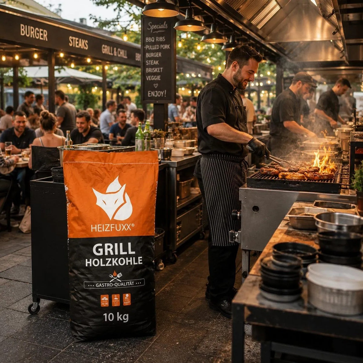 Heizfuxx Grillholzkohle 10kg Gastro-Qualität Sack vor Grillstand mit Köchen, die Fleisch grillen. Hochwertige Brennstoffe für Profis.
